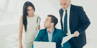 Two men and a woman looking at a laptop